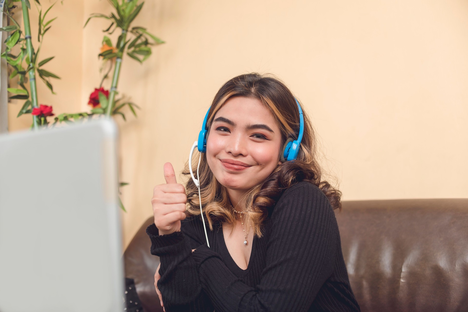 A portrait of a vlogger showing a thumbs up sign to show approval. She is wearing a blue wired headset.